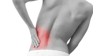 Persona con dolor lumbar izquierdo, con la mano apoyada en la zona afectada, resaltada en rojo.