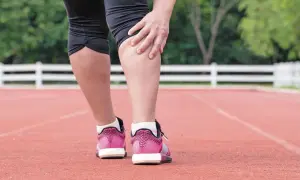 Corredora se toca la pierna, sintiendo dolor en el gemelo musculo tras el esfuerzo.