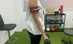 Persona con banda de oclusión en el brazo realiza ejercicios con mancuerna, parte de la rehabilitacion fractura humero ejercicios.
