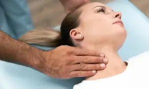 Manos de terapeuta ajustando el cuello rectificado de una mujer en una camilla.