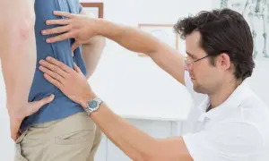 Fisioterapeuta evalúa la espalda de un paciente, aplicando el método Schroth para corregir la postura.