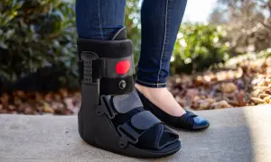 Piernas con jeans y una bota walker negra. Se puede quitar la bota walker para dormir, permitiendo usar un zapato cómodo.