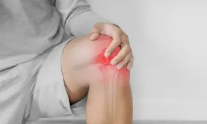 Hombre tocando su rodilla con un área roja brillante que indica dolor y sensación de quemazón.