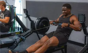 Hombre sonriendo mientras hace remo, un excelente ejercicio de cardio.