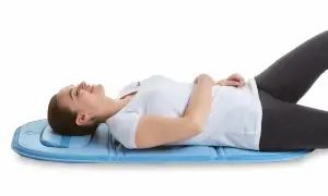 Mujer tumbada en colchoneta azul, experimentando alivio para su hernia discal con magnetoterapia.