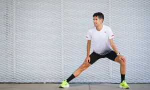 Corredor realiza estiramientos antes de correr, preparándose para su entrenamiento.