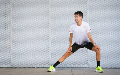 Corredor realiza estiramientos antes de correr, preparándose para su entrenamiento.