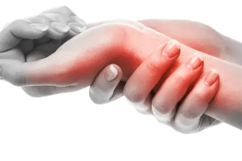 Manos con área roja en la muñeca, indicando dolor. El **sinovitis tratamiento fisioterapia** puede aliviar esta inflamación.
