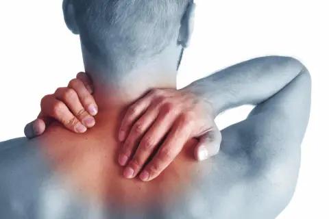 Hombre con dolor de cuello y hombros, sintiendo los síntomas de cervicales.