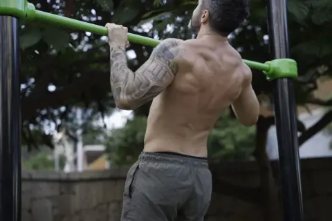 Hombre realizando dominadas, mostrando la fuerza de sus bíceps y espalda. Los músculos implicados en las dominadas son clave para este ejercicio.