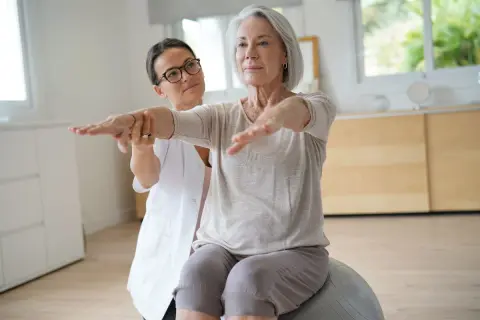 Fisioterapeuta ayuda a una mujer mayor a mejorar su equilibrio y fuerza, trabajando en diferentes niveles de Berg.