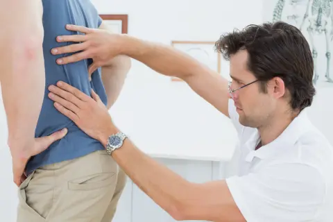 Fisioterapeuta evalúa la espalda de un paciente, aplicando el método Schroth para corregir la postura.