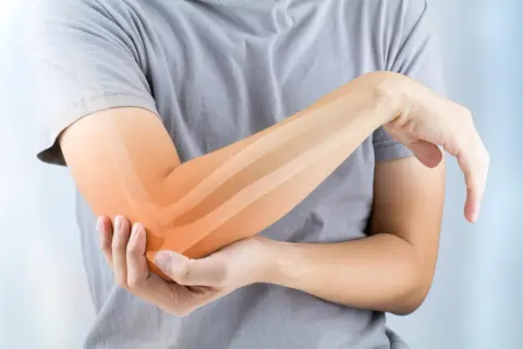 Persona con dolor en el codo, resaltando los ligamentos del codo con un tono naranja.
