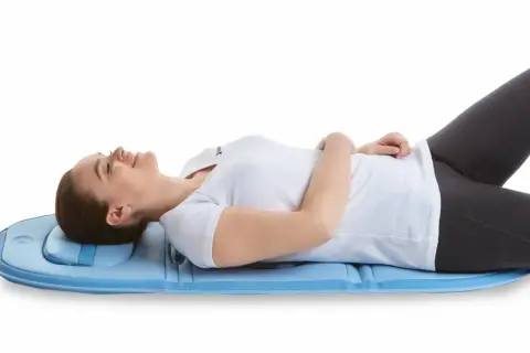 Mujer tumbada en colchoneta azul, experimentando alivio para su hernia discal con magnetoterapia.