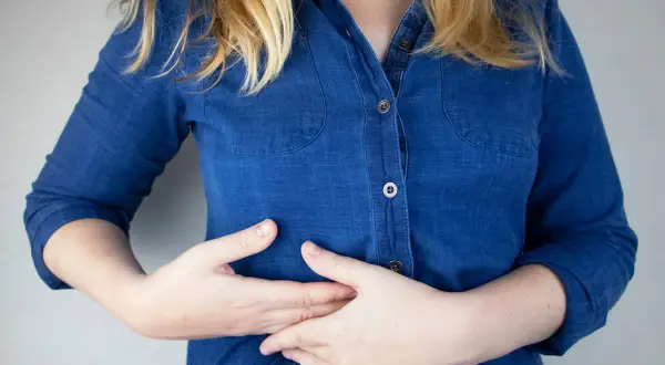 Persona con dolor costilla flotante derecha, se lleva las manos al abdomen.