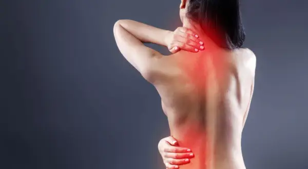Mujer con dolor en la espalda alta, sintiendo la molestia de la artrosis.