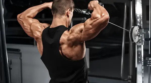 Hombre musculoso entrenando el deltoides posterior con polea.