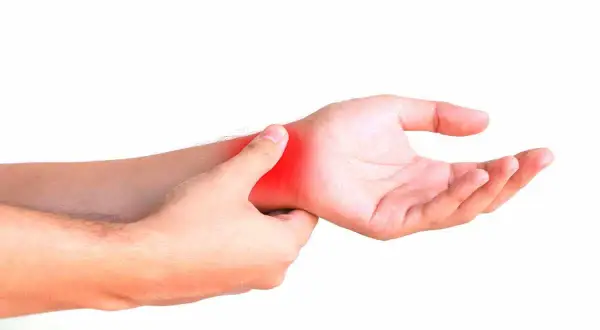 Una mano se presiona la muñeca, con una zona roja indicando dolor. ¿Cómo saber si tengo la muñeca abierta?