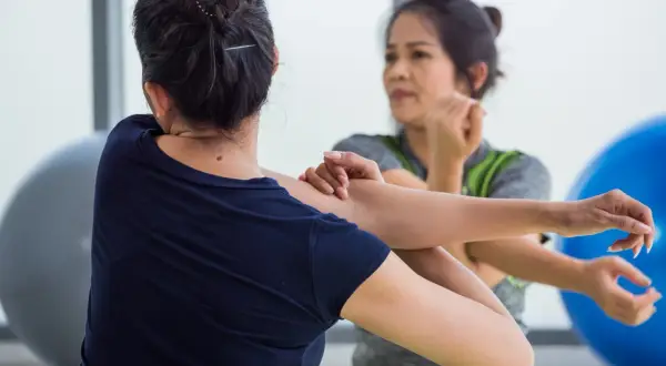 Dos mujeres estiran sus brazos, enfocándose en el músculo braquial bíceps.
