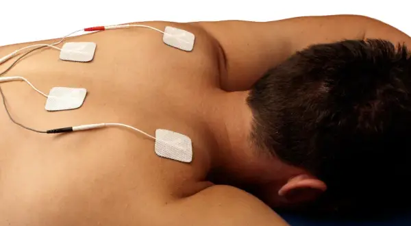Electrodos colocados en la espalda de un hombre para tratamiento de electroterapia en fisioterapia.