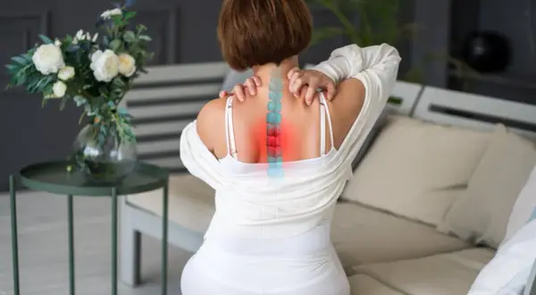 Mujer con dolor de espalda, visualización de la columna vertebral con zonas rojas indicando dorsalgia mecánica.