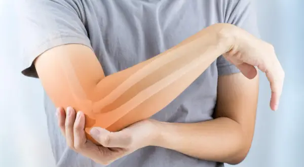 Persona con dolor en el codo, resaltando los ligamentos del codo con un tono naranja.