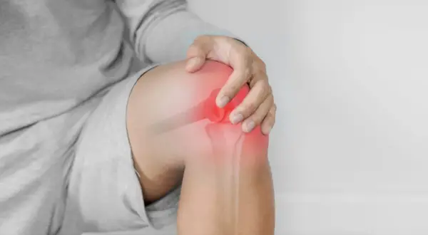 Hombre tocando su rodilla con un área roja brillante que indica dolor y sensación de quemazón.