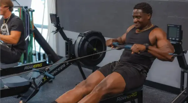 Hombre sonriendo mientras hace remo, un excelente ejercicio de cardio.