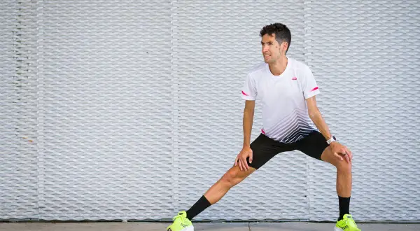 Corredor realiza estiramientos antes de correr, preparándose para su entrenamiento.