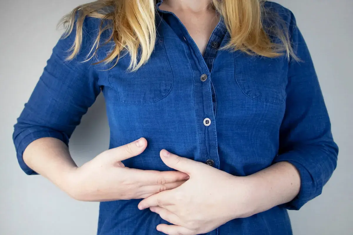Persona con dolor costilla flotante derecha, se lleva las manos al abdomen.