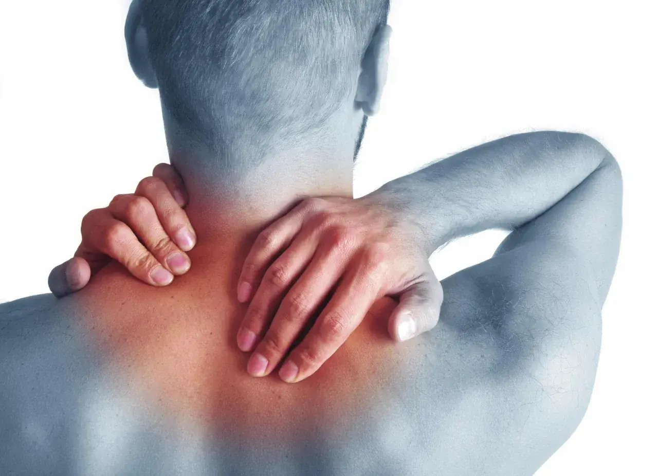 Hombre con dolor de cuello y hombros, sintiendo los síntomas de cervicales.