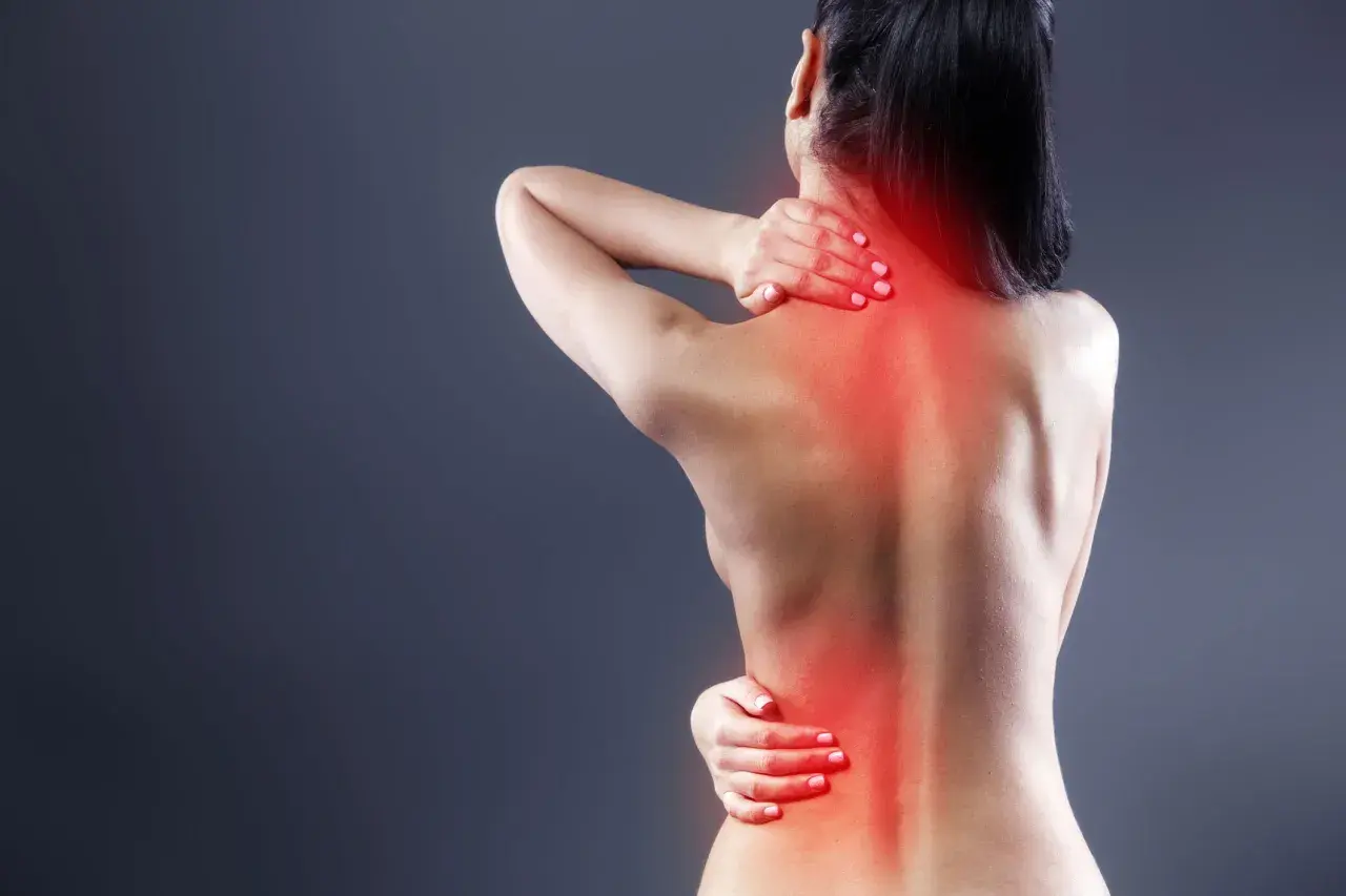 Mujer con dolor en la espalda alta, sintiendo la molestia de la artrosis.