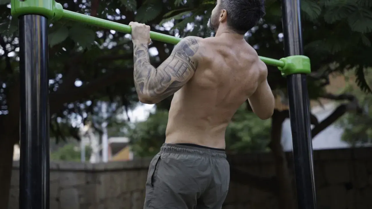 Hombre realizando dominadas, mostrando la fuerza de sus bíceps y espalda. Los músculos implicados en las dominadas son clave para este ejercicio.