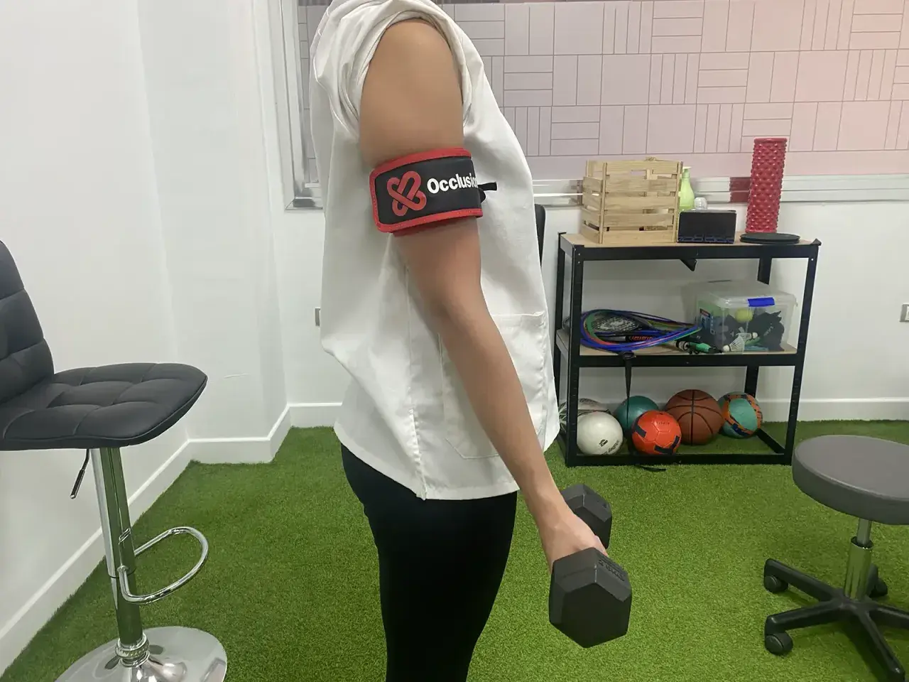 Persona con banda de oclusión en el brazo realiza ejercicios con mancuerna, parte de la rehabilitacion fractura humero ejercicios.