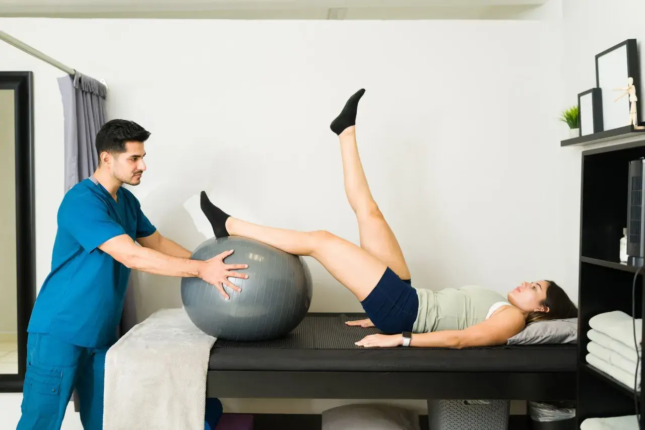 Fisioterapeuta ayuda a paciente con hiperlordosis lumbar ejercicios usando balón.