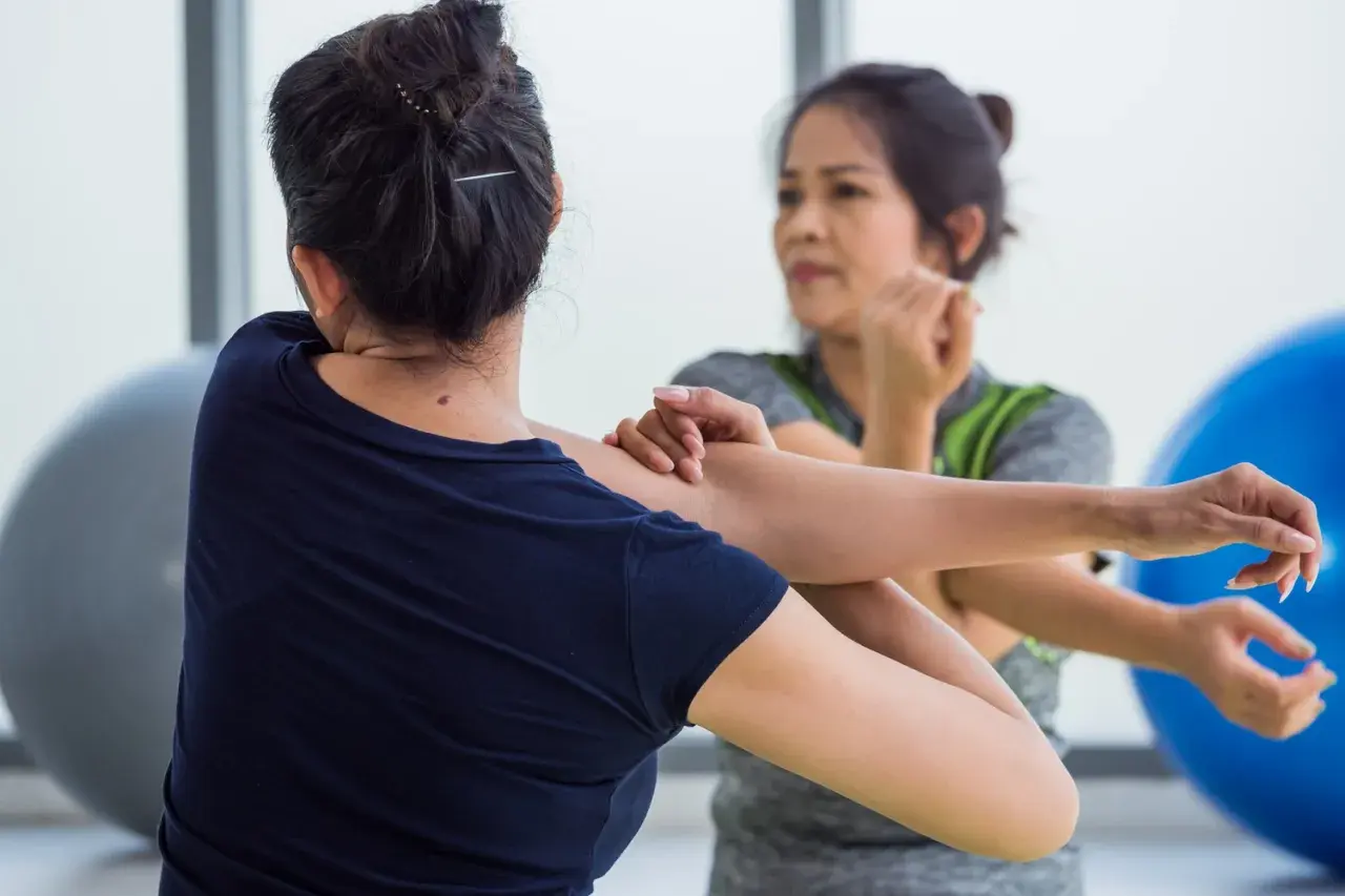 Dos mujeres estiran sus brazos, enfocándose en el músculo braquial bíceps.