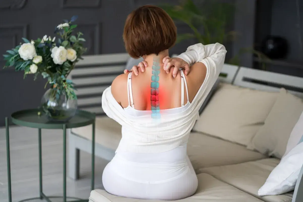 Mujer con dolor de espalda, visualización de la columna vertebral con zonas rojas indicando dorsalgia mecánica.