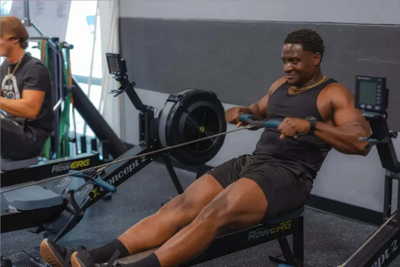 Hombre sonriendo mientras hace remo, un excelente ejercicio de cardio.