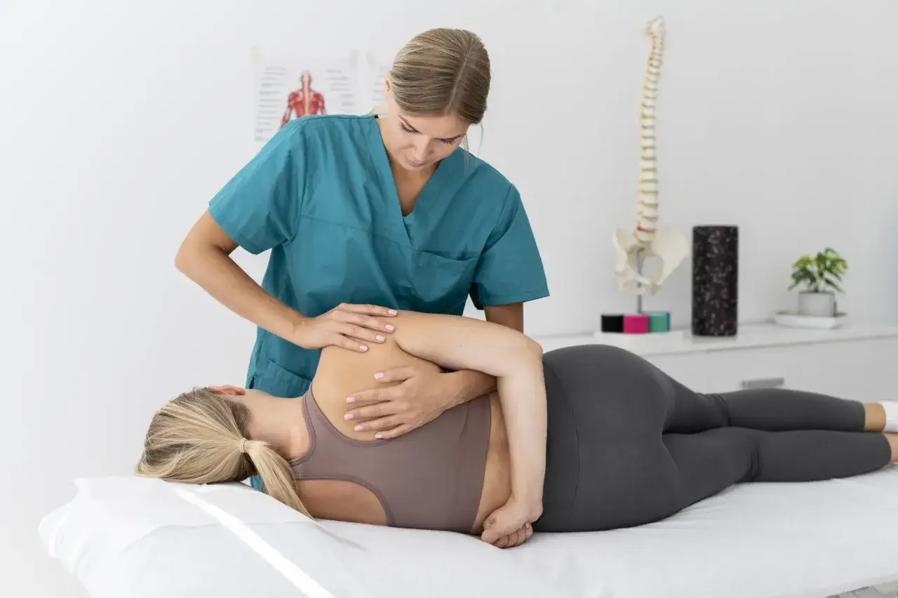 Fisioterapeuta realiza masaje en la espalda de una paciente acostada en una camilla.