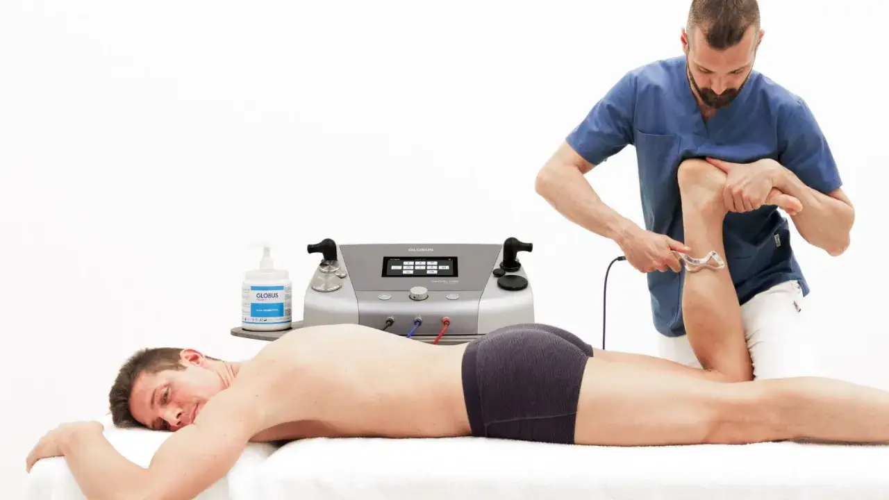 Fisioterapeuta aplica diatermia capacitiva y resistiva en la pierna de un paciente con equipo Globus.