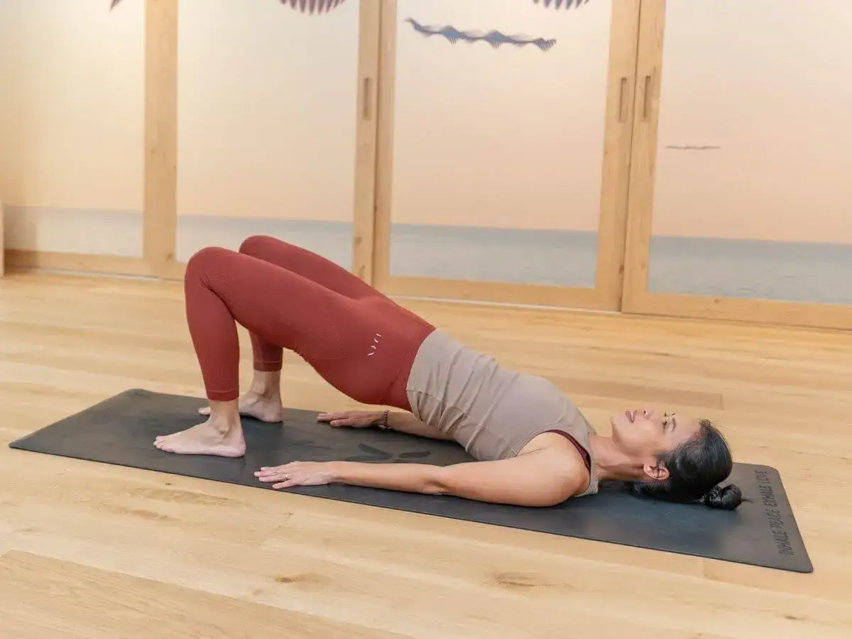 Mujer haciendo yoga en postura de puente para aliviar la espalda baja.
