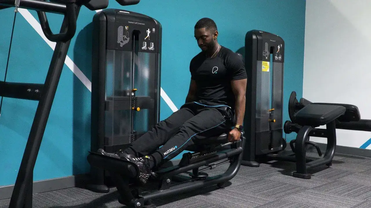 Hombre realizando ejercicios de soleo en m&aacute;quina de gimnasio.