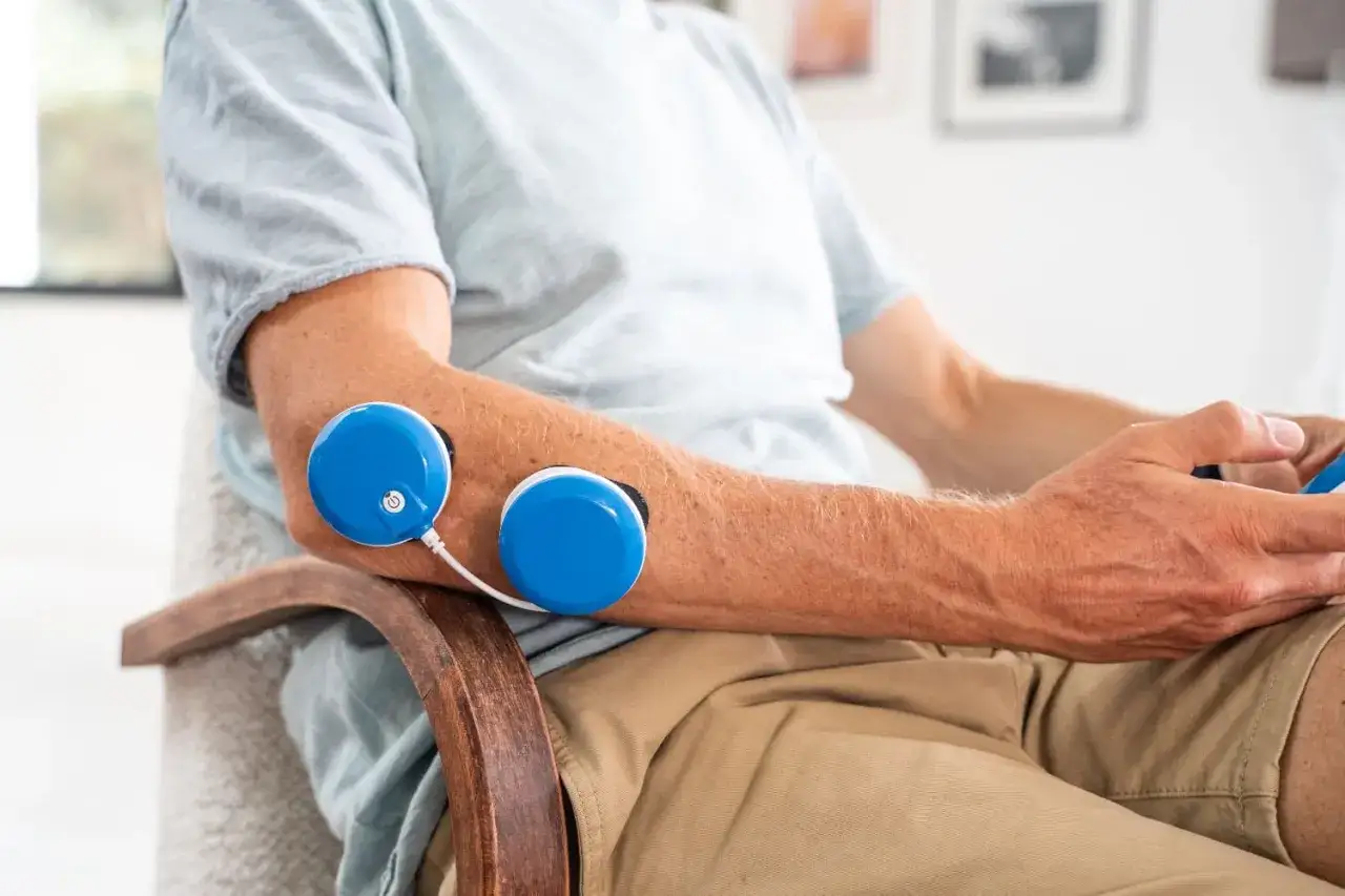 Hombre con dispositivo de magnetoterapia epicondilitis en el codo.