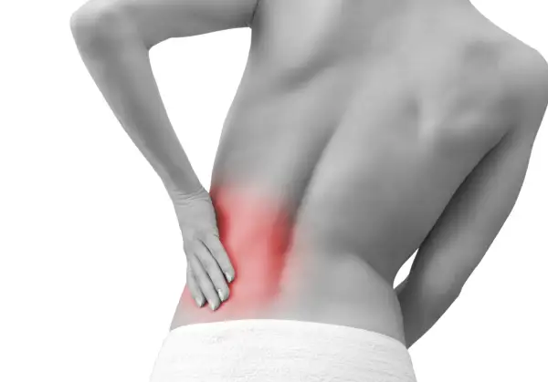 Persona con dolor lumbar izquierdo, con la mano apoyada en la zona afectada, resaltada en rojo.