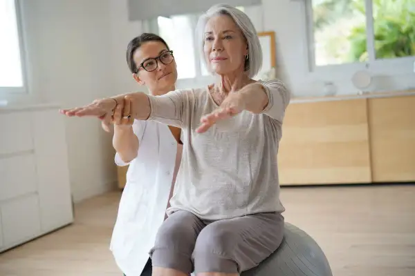 Fisioterapeuta ayuda a una mujer mayor a mejorar su equilibrio y fuerza, trabajando en diferentes niveles de Berg.