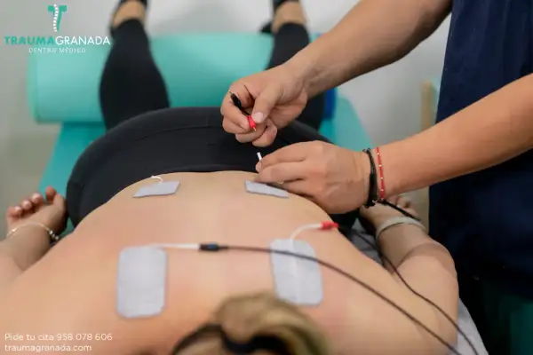 Fisioterapeuta aplica electroestimulación en la espalda de un paciente. Un tratamiento para aliviar el dolor y mejorar la recuperación muscular.