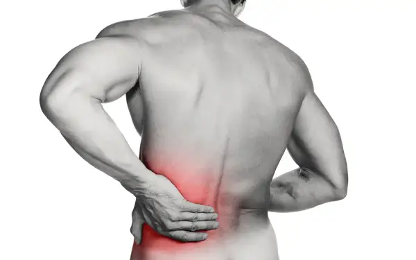 Hombre con mano en la espalda baja, zona roja indica dolor lumbar.
