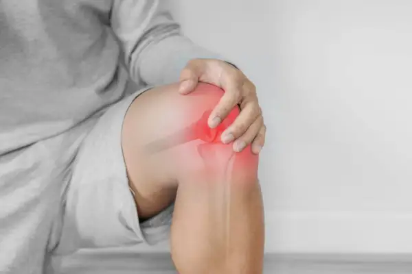Hombre tocando su rodilla con un área roja brillante que indica dolor y sensación de quemazón.