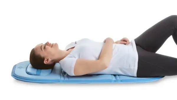 Mujer tumbada en colchoneta azul, experimentando alivio para su hernia discal con magnetoterapia.