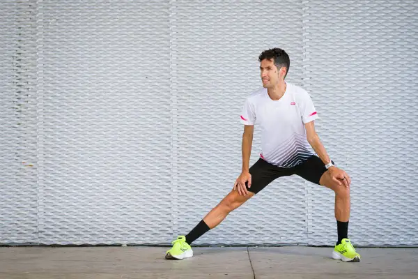 Corredor realiza estiramientos antes de correr, preparándose para su entrenamiento.
